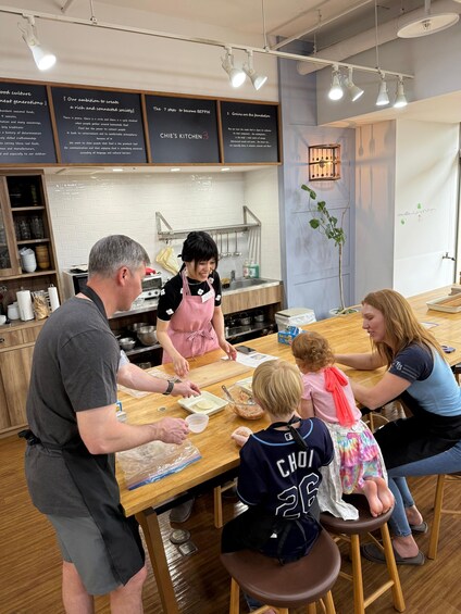A family cooking together in a kitchen with wooden countertops and hanging lights. 5