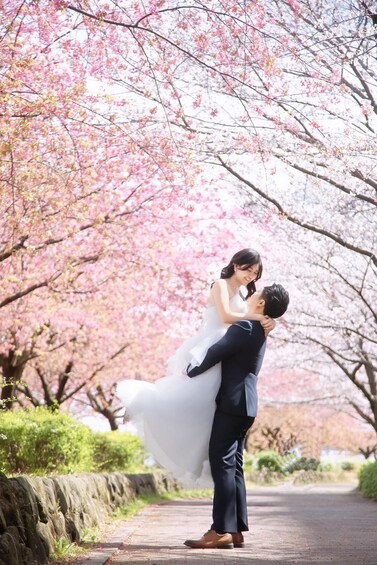 A couple embracing in a park with cherry blossoms. 1