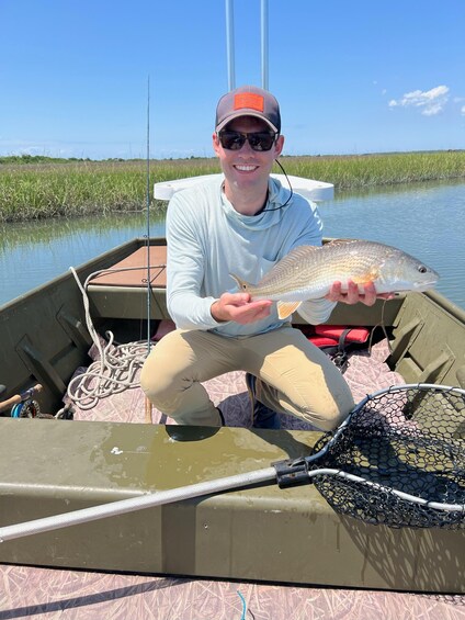 A person holding a fish on a boat in a calm water body with reeds in the background. 5