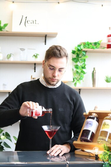 A person pouring a red liquid into a martini glass. 2