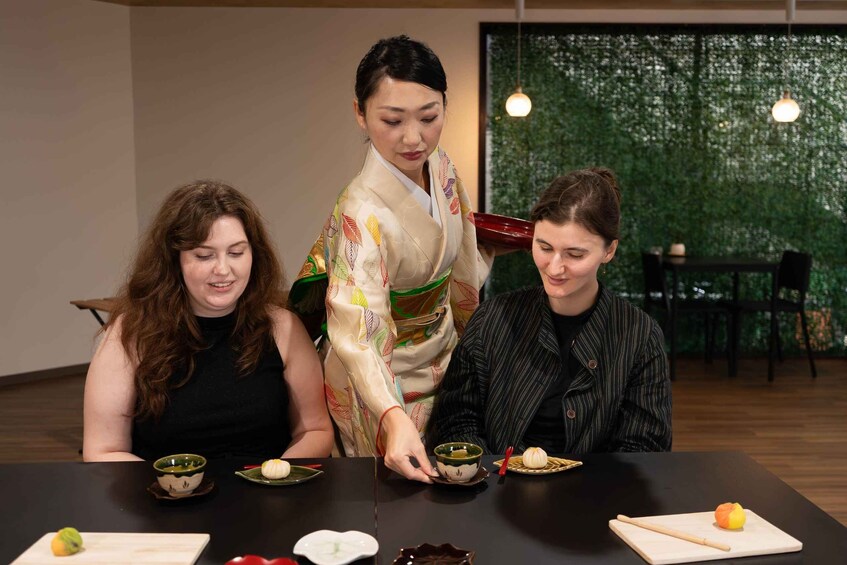 Three people seated at a table with traditional Japanese dishes, one person in a kimono. 2