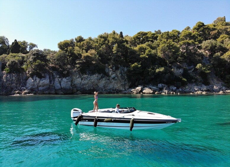 A boat on turquoise water with a rocky coastline and dense trees in the background. 3