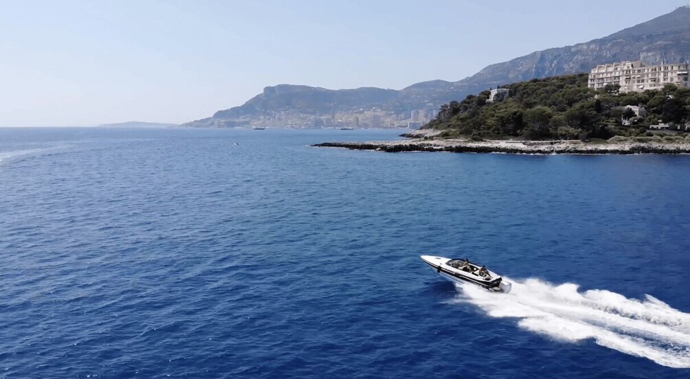 A speedboat on a calm sea with a mountainous coastline in the background. 2