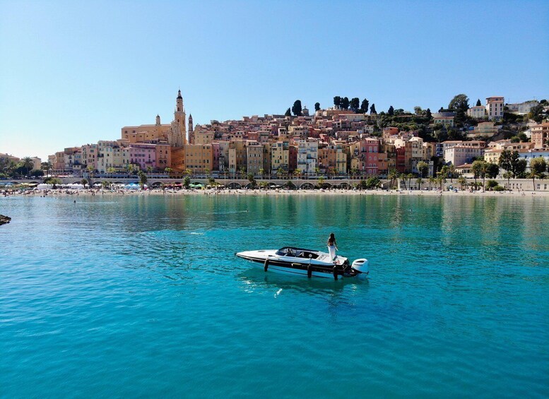 A coastal town with a prominent church tower, a boat on the water, and a densely packed hillside of colorful buildings. 4