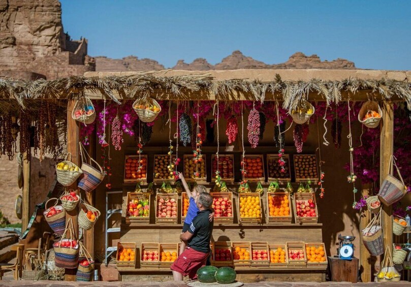 A fruit stand with baskets and crates of various fruits in a desert setting. 2
