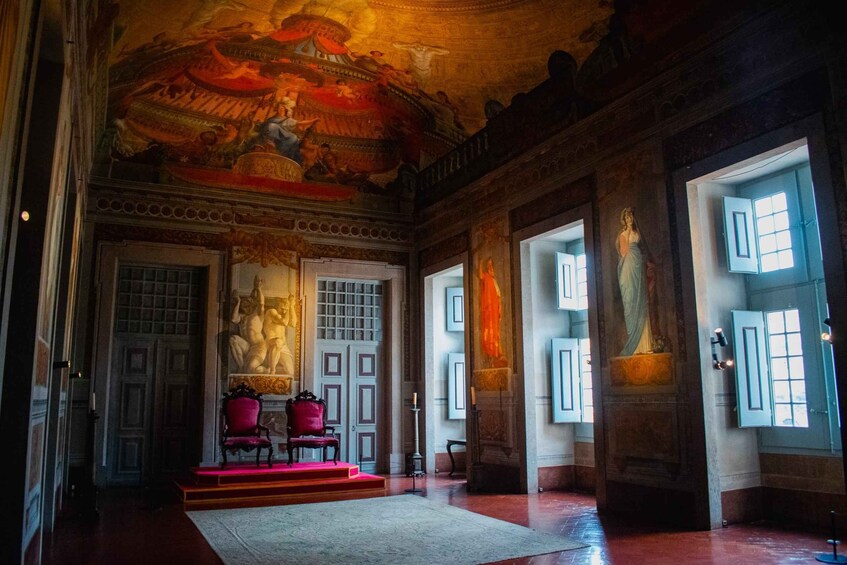 An ornate room with a large mural, red chairs, and a statue. 3