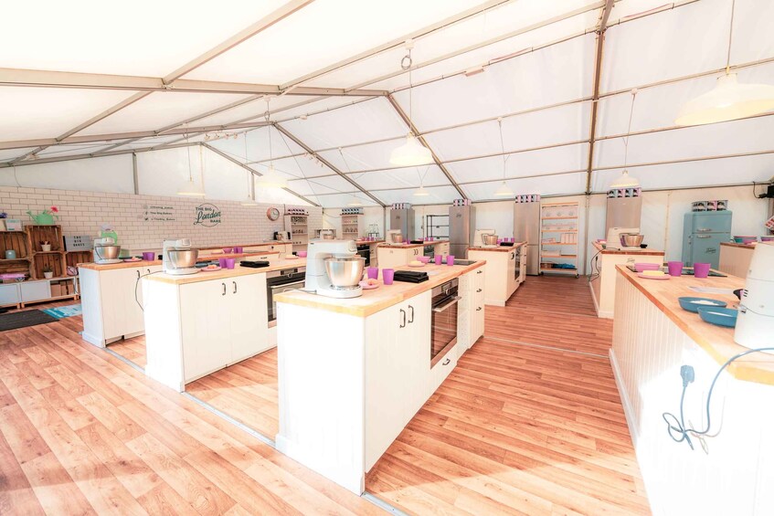 A spacious tented kitchen with wooden flooring, white cabinetry, and various cooking utensils. 4