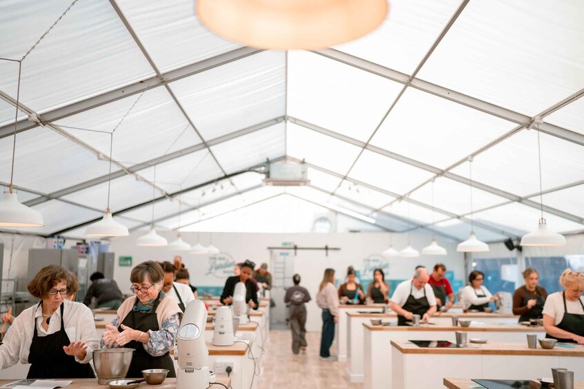 A tented indoor market with people shopping and vendors selling goods. 3