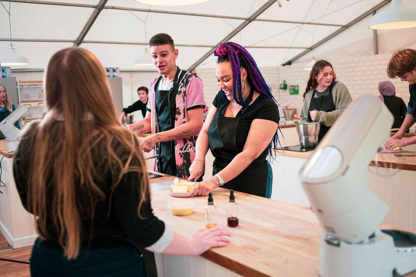 A group of people in a food preparation area with a digital ordering kiosk and a robotic kitchen assistant. 2