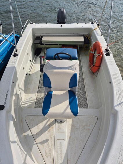 A boat's interior with a steering wheel, blue and white seats, a life preserver, and a Yamaha outboard motor. 2
