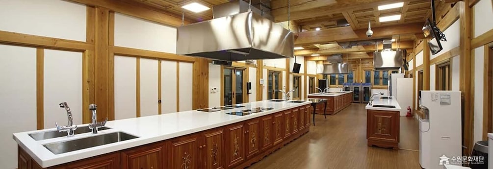A spacious kitchen with wooden cabinets, a long countertop, and stainless steel appliances. 5