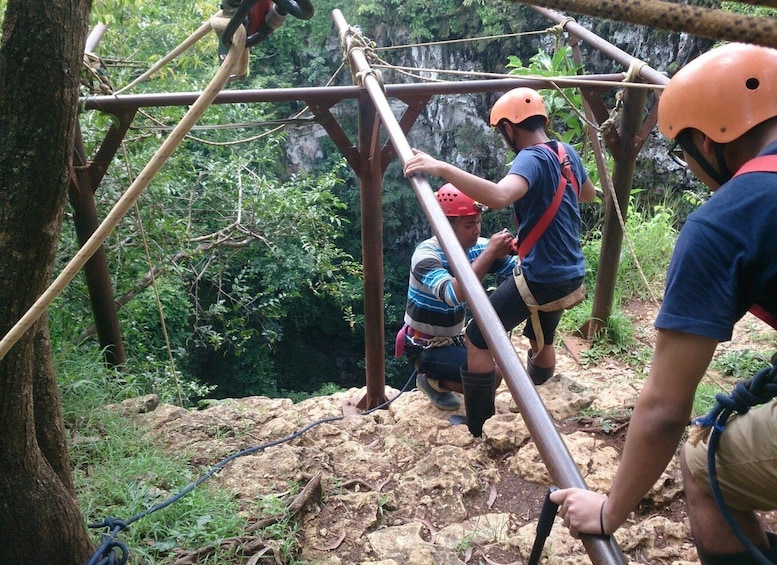 A group of people engaged in a ropes course activity in a forested area with wooden structures and ropes. 4