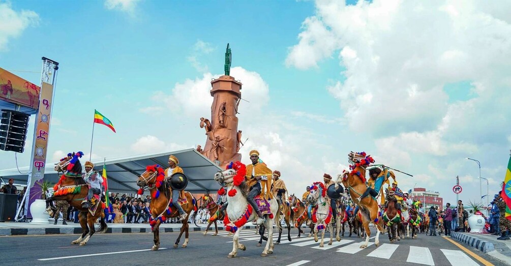 A parade with people on decorated horses, a large tower, and a crowd watching. 2