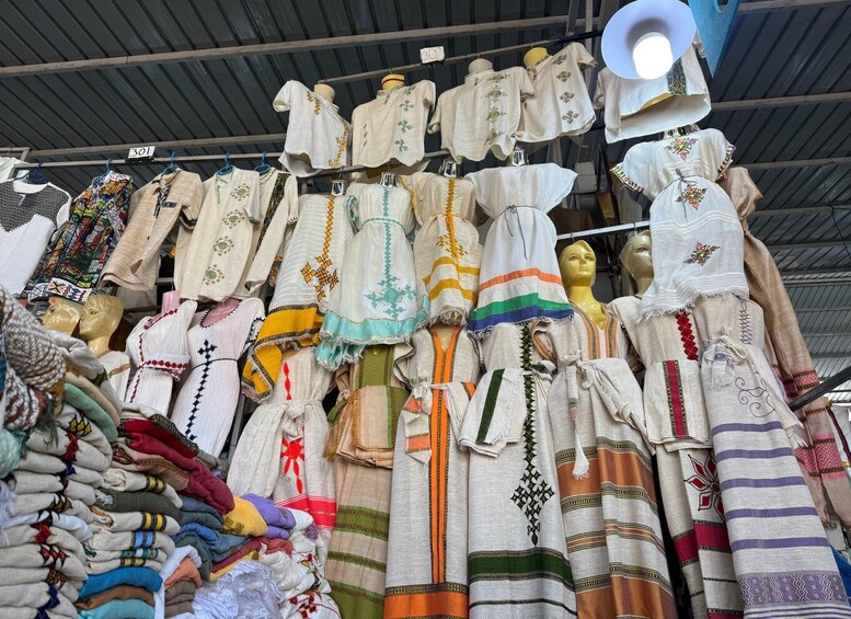 A variety of traditional garments displayed on mannequins and hangers, including embroidered shirts and skirts with intricate patterns. 4