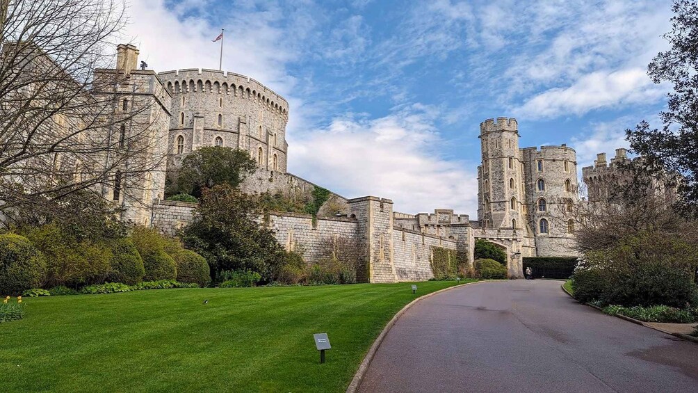 A historic stone castle with a round tower, surrounded by well-maintained lawns and trees. 4
