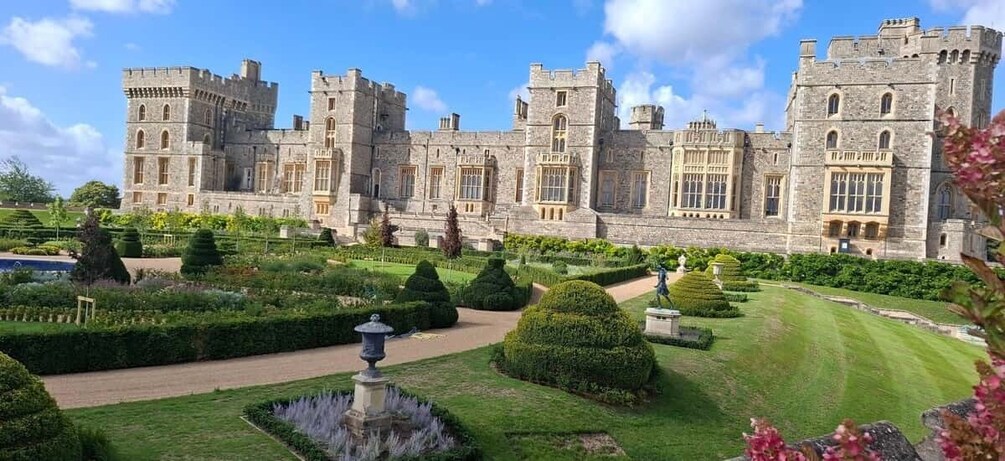 A large castle with a well-manicured garden, including hedges and a central fountain. 1