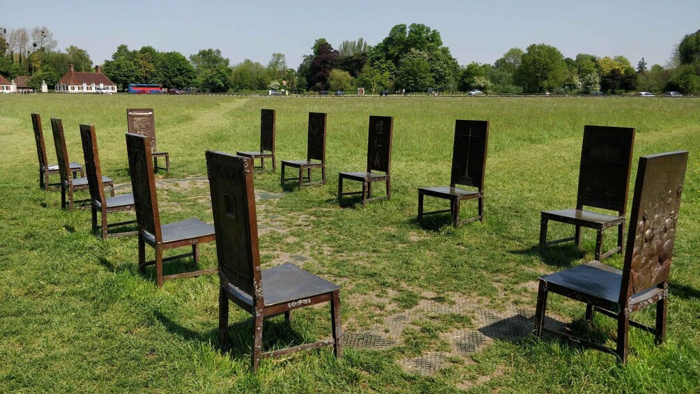 A grassy field with wooden chairs arranged in a circle. 3