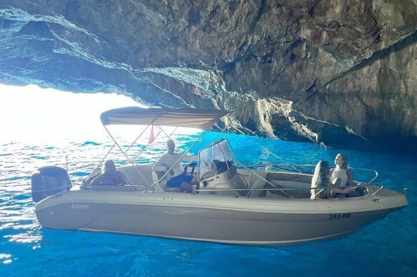 A boat with people on it near a rocky coastline. 3