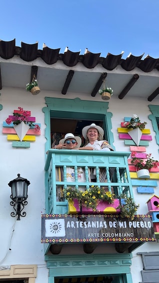 A colorful building with a balcony, decorative flower pots, and a sign reading 'ARTESANIAS DE MI PUEBLO ARTE COLOMBIANO.' 2