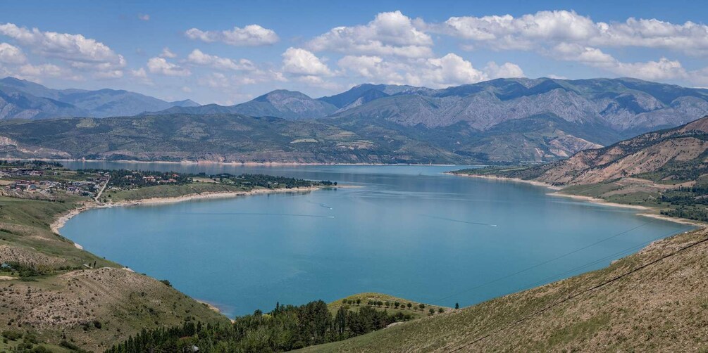 A large lake surrounded by mountains, a small town, and a clear sky. 1
