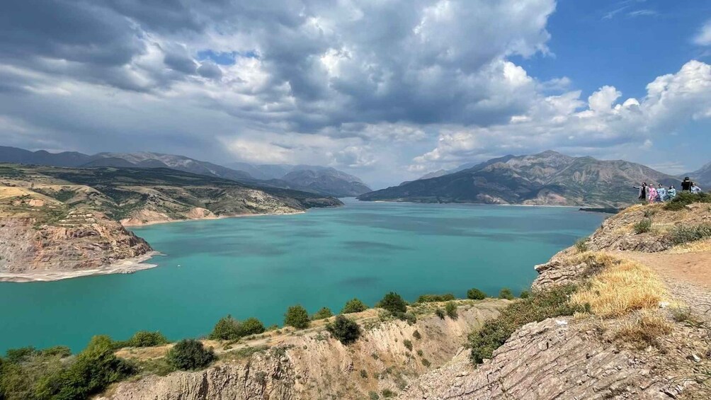 A turquoise lake surrounded by mountains and a cloudy sky. 2