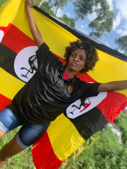 A person holding a flag with a bird emblem, wearing a black shirt with a logo, and denim shorts. 3