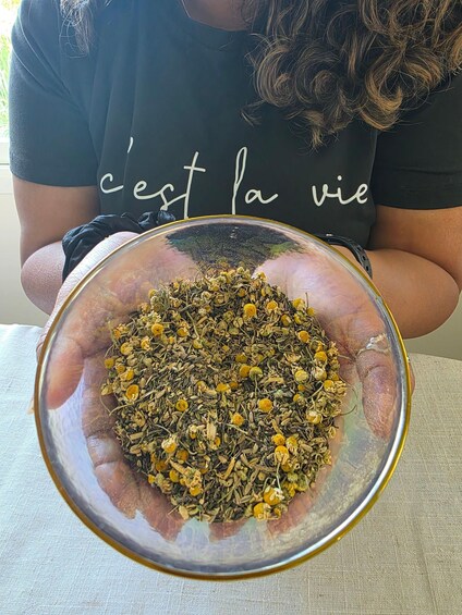 A person holding a bowl of dried herbs. 2