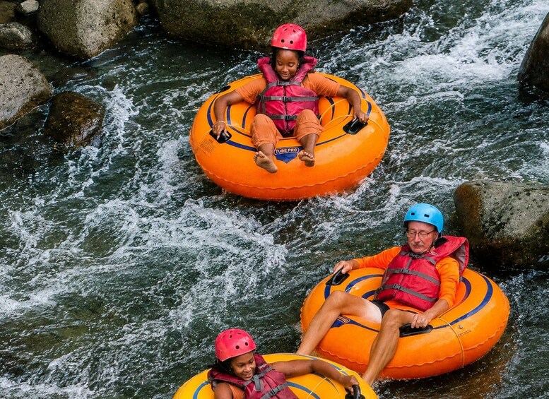 Three people rafting down a river in inflatable tubes. 5