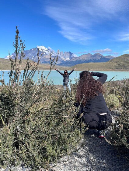 Two people in a natural landscape with a lake and mountains in the background. 2