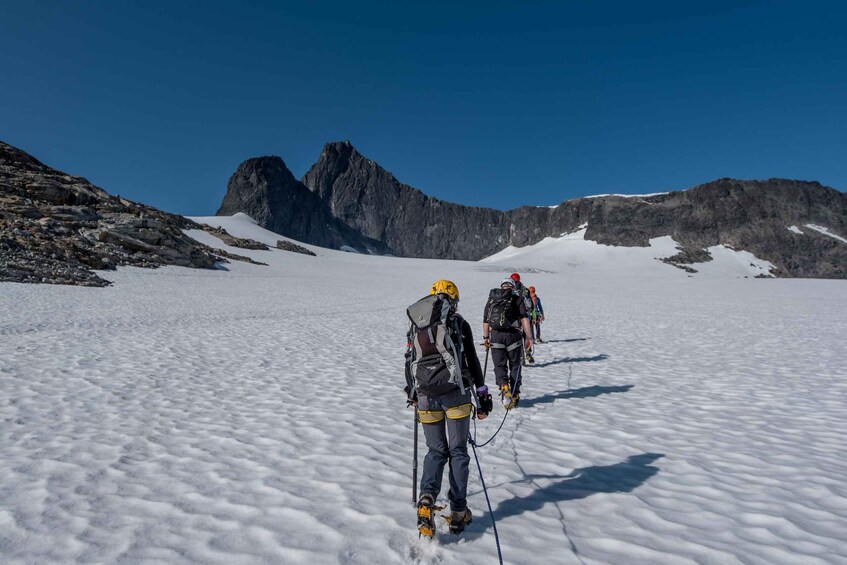 A group of climbers on a snowy mountain with rocky terrain and a clear sky. 2