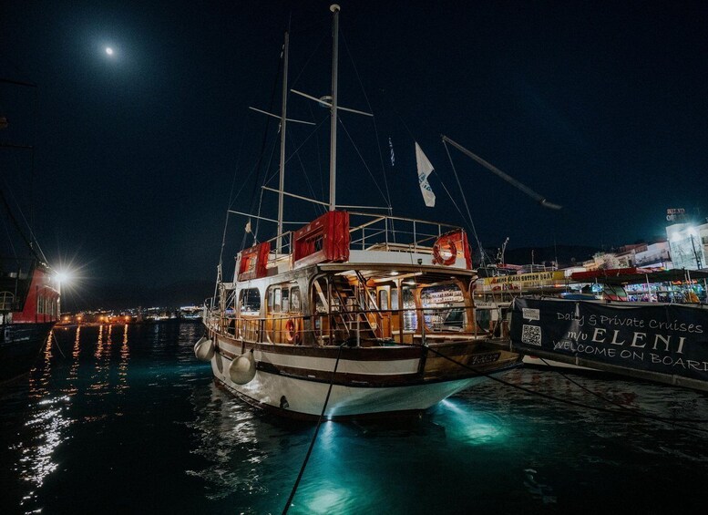 A boat docked at a marina with city lights in the background. 4