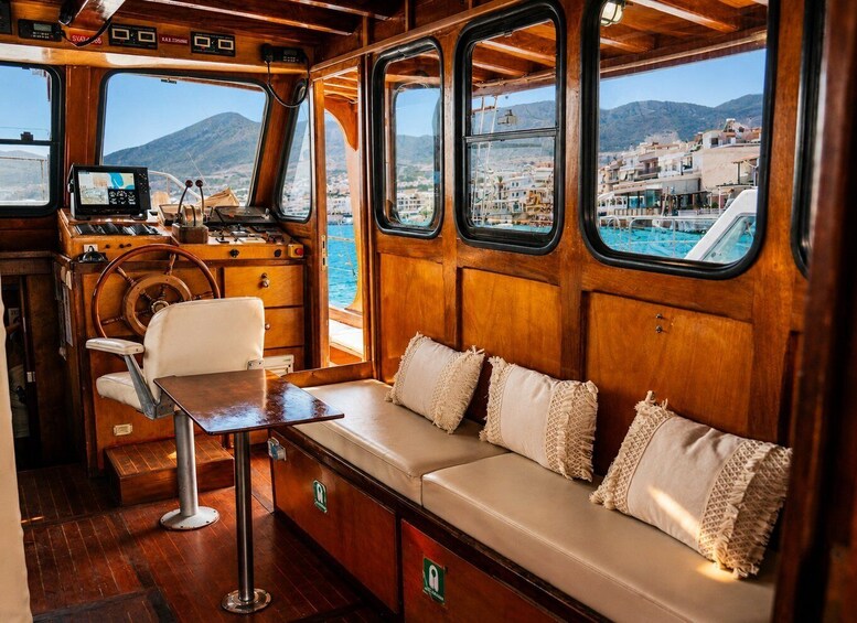 A boat's interior with a wooden bench, a steering wheel, and a control panel. 3