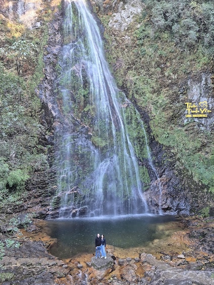 A waterfall cascading down a rocky cliff into a clear pool surrounded by lush greenery. 2