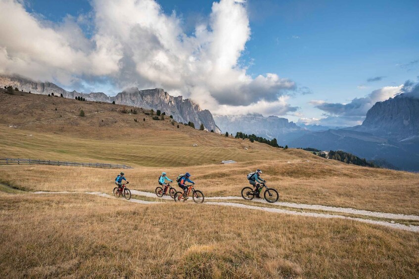 A group of cyclists on a dirt trail in a mountainous area with rocky outcrops and a clear sky. 5