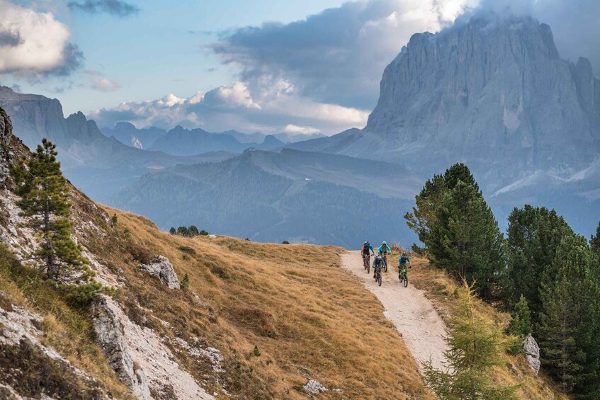 A group of cyclists on a mountain trail surrounded by rugged terrain and distant peaks. 2
