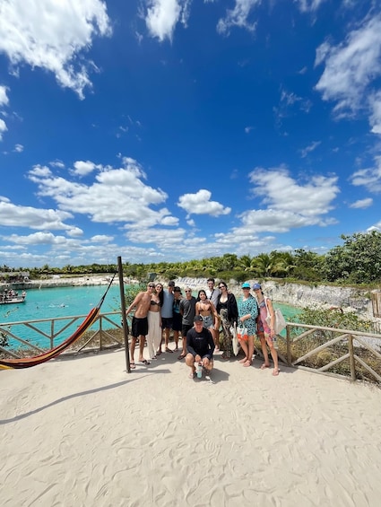 A group of people on a beach with a hammock, a clear blue sky, and a calm sea. 2