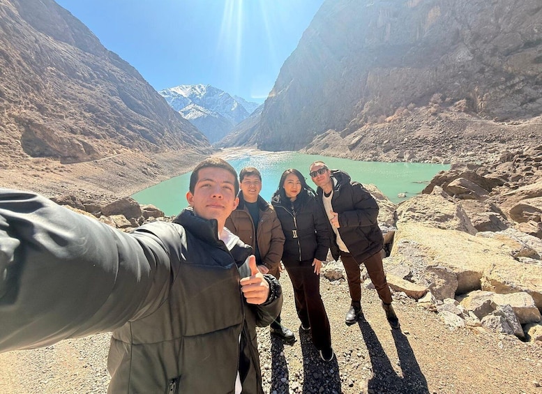 A group of people taking a selfie in a mountainous area with a lake. 5