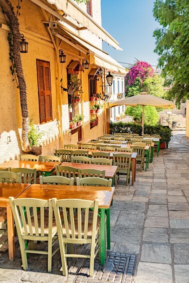 Outdoor cafe seating with tables and chairs, potted plants, and a building with a yellow facade. 5