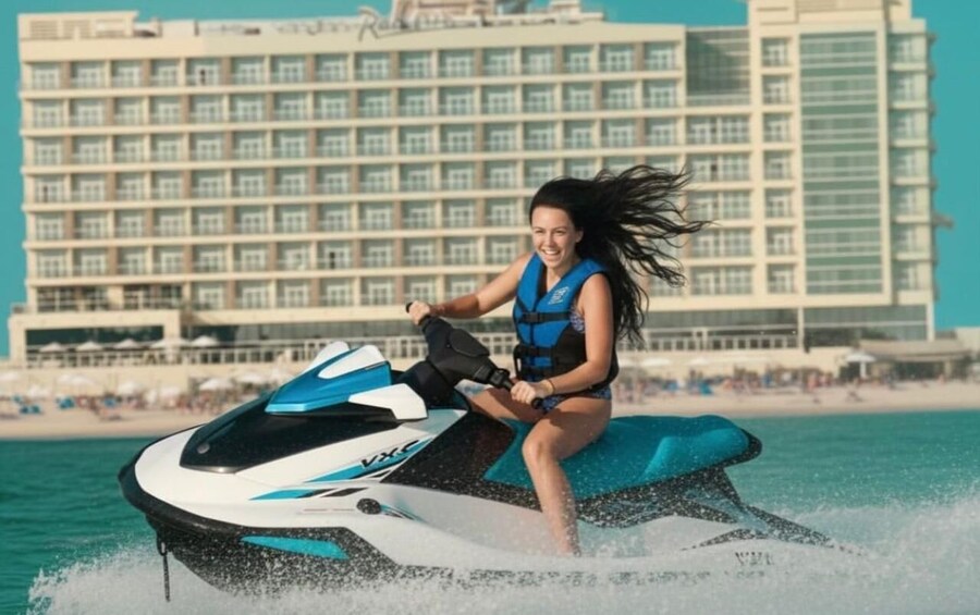 A person jet-skiing on a body of water with a large hotel in the background. 1