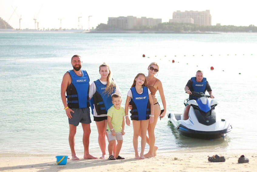 A family on a beach with a jet ski and a boat in the background. 2