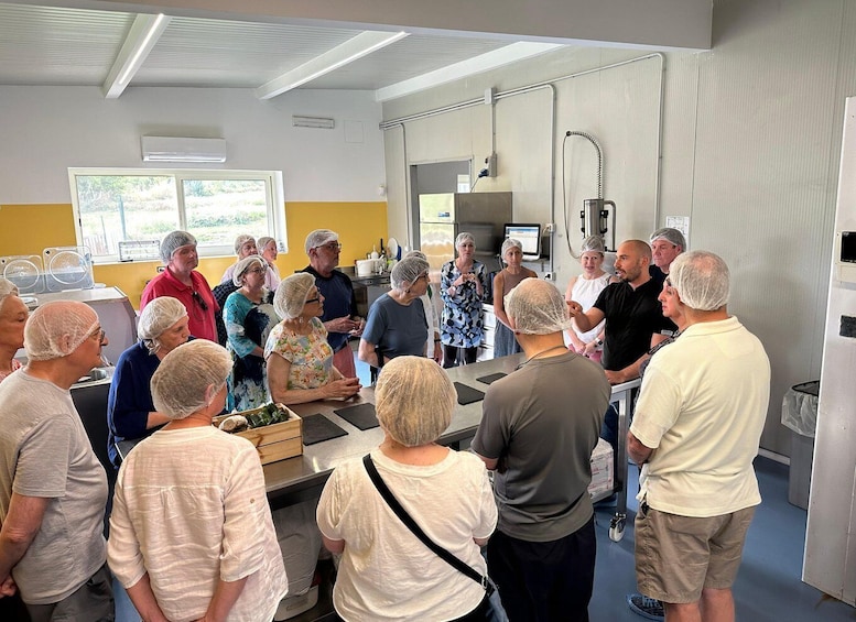 A group of people in a kitchen, some wearing hairnets, gathered around a table with food items. 3