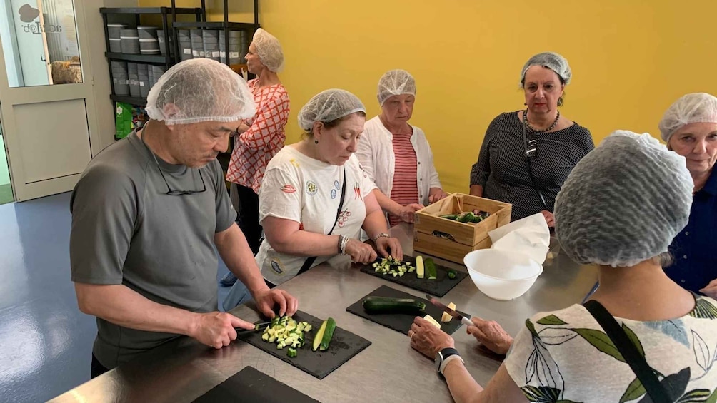 A group of people preparing food, with vegetables on cutting boards and a wooden crate in the background. 2