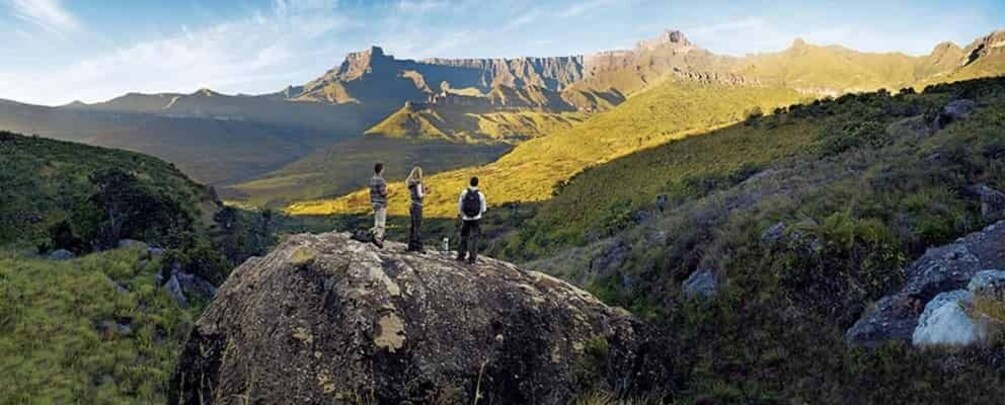 Two people standing on a rock with a mountainous landscape in the background. 4