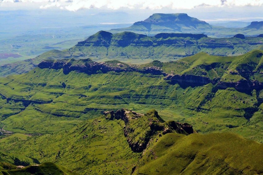 A mountainous landscape with rolling hills and a prominent peak in the distance. 3