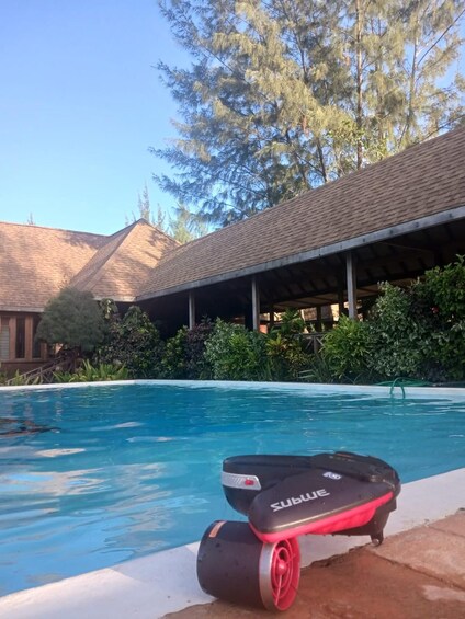 A swimming pool with a water slide, surrounded by trees and a covered patio. 2