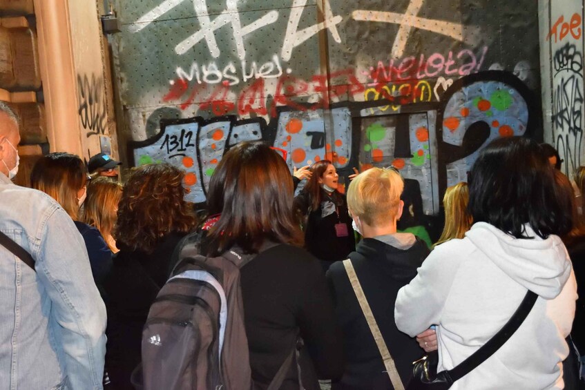 En menneskemængde har samlet sig foran en væg med graffiti. 1
