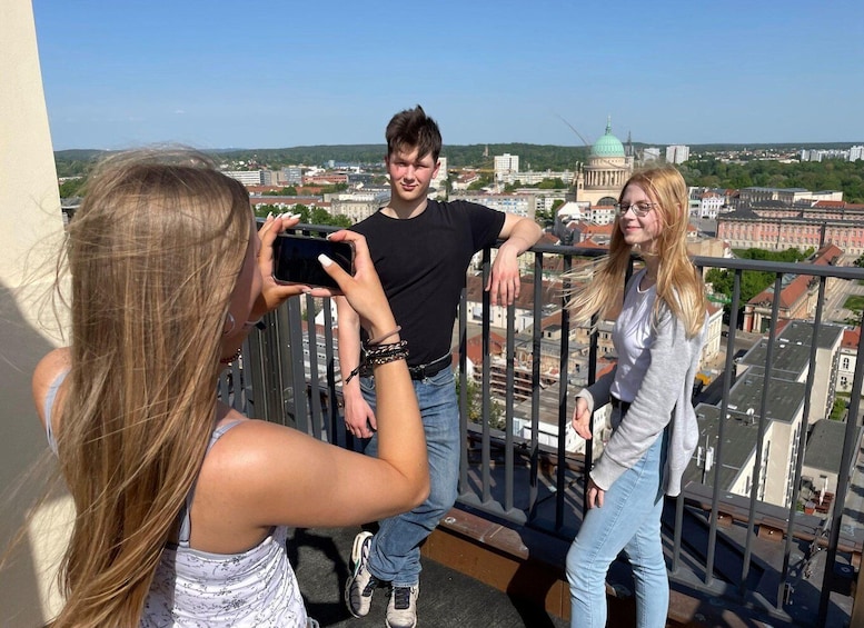 A group of people on a balcony overlooking a cityscape with buildings and a dome structure. 3