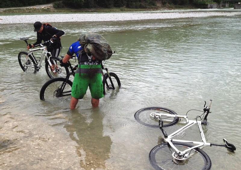 Two cyclists crossing a shallow river with their bicycles. 3