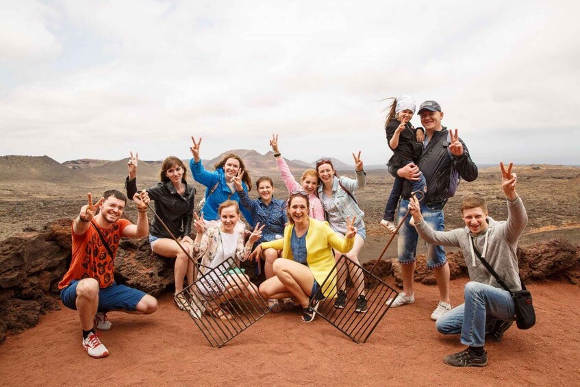 A group of people posing with peace signs in a barren landscape with red soil and distant hills. 2
