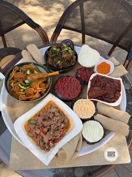 A variety of Ethiopian dishes including injera, stews, and sauces on a table. 1